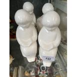 Four white sand filled ceramic figures of seated child reading