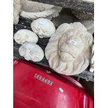 A lion's head concrete garden ornament and 3 funny faces concrete ornaments.