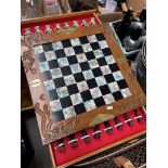 An Oriental carry case chess board with drawers, complete with figural pieces.
