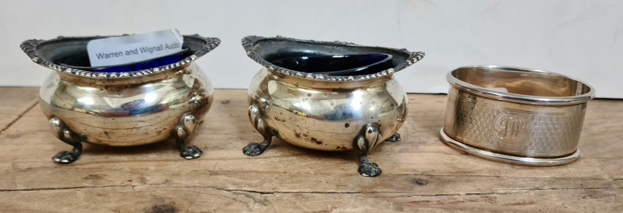 A pair of silver salts with cobalt blue glass liners and a silver napkin ring, hallmarked for