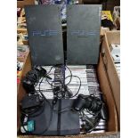 A box containing 3 Playstation 2's, accessories and a collection of games.