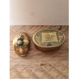 A brass snuff box, hinged, 1917 penny and UBIQUE cap badge and a brass tobacco box of oval shape,