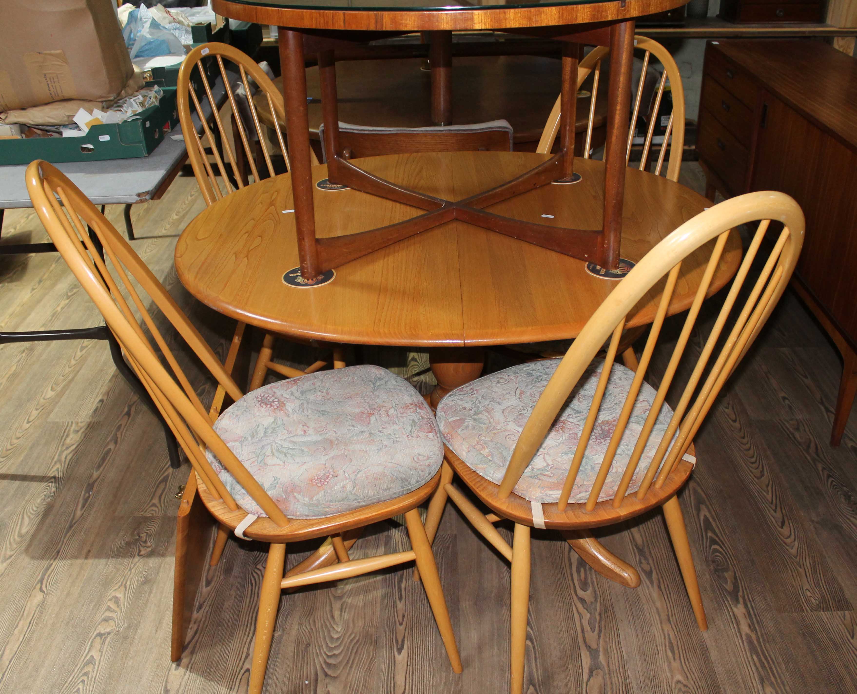 An Ercol oval extending pedestal table and four chairs, with one extension leaf.