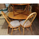 An Ercol oval extending pedestal table and four chairs, with one extension leaf.