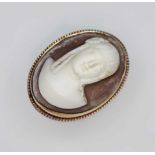 A shell cameo ring, the oval cameo carved in relief depicting a female bust, bezel mount with rope