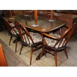 An Ercol dark beech and elm refectory table with six Ercol 'Windsor' dining chairs including two