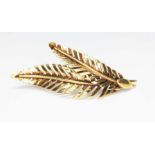 A modern brooch formed from two fern leaves, marked '585', length 44mm, wt. 3.8g.