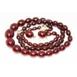 A graduated slightly marbled cherry bakelite bead necklace, bracelet and earrings, beads ranging