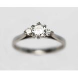 A three stone diamond ring, the central six claw set round brilliant cut diamond weighing approx.