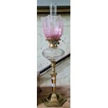 A Victorian brass oil lamp with cut glass reservoir and pink etched glass shade.