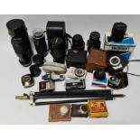 A box of camera equipment including lenses, tripod, vintage light meters etc.