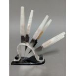 An Art Deco marble effect and black bakelite knife stand with six knives, the serrated steel