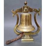A brass bell with rope, mounted on a brass stand.