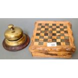 A wooden chess board box containing chess set and dominoes together with an old desk bell.