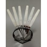 An Art Deco marble effect and black bakelite knife stand with six knives, the serrated steel