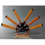 An Art Deco black and butterscotch bakelite knife stand with six knives, the steel blades marked '