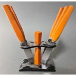 An Art Deco bakelite knife stand with a set of six orange bakelite handled knives, the serrated