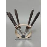 An Art Deco knife stand of round form with six wooden handled knives having steel blades marked '