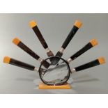 An Art Deco black and butterscotch bakelite knife stand with six knives, the steel blades marked '