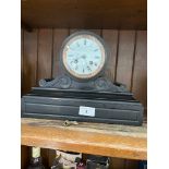 An early 20th century black slate mantel clock with enamelled face, key and pendulum.