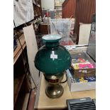 A brass oil lamp with green glass and clear funnel