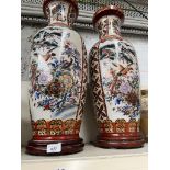 Pair of Chinese vases decorated with birds and flowers, both on wooden bases.