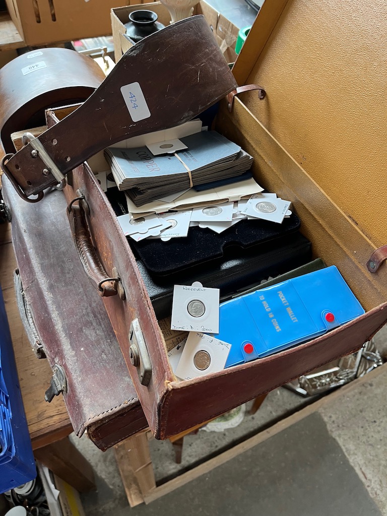 A vintage leather case containing coin wallets and loose American coins, a leather case and a belt.