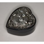 A silver topped heart shaped leather ring or trinket box, embossed with cherubs amongst clouds,