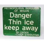 A green and white painted metal sign "METROPOLITAN BOROUGH OF WIGAN Danger Thin ice keep away BY