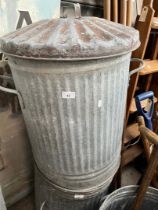 A galvanised dust bin with lid.