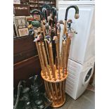 A circular wood display stand and large selection of ornamental long walking sticks with bird heads.