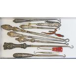 A collection of mainly hallmarked silver handled and other button hooks, together with an enamel "