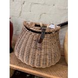 A wicker fishing basket containing various vintage fishing reels.