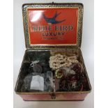 A tin box containing various antique and vintage costume jewellery to include vulcanite, jet, glass,