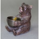 A Black Forest carved vesta stand modelled as a bear holding a brass bowl height 8cm.