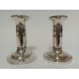 A pair of hallmarked silver candlesticks with swag and bow decoration, height 9cm.