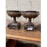 A pair of spelter urns on marble bases with gilt ball feet, part of a clock garniture.