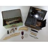 A vintage tin box containing various collectables including a WW1 bone letter opener, tusk,