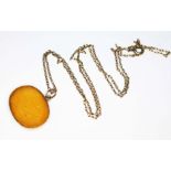 An eastern yellow metal mounted and engraved yellow hardstone pendant on chain, unmarked, gross