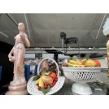 Two large ceramic fruit bowls with various fruits and a figure of a lady.