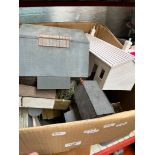 A box of model railway trackside buildings, some home made, and other accessories