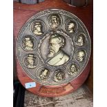 A wooden shield with a Brass circular plaque of Charles Dickens with charcters from his books on the