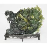 A Chinese jadeite jade carving depicting four carp and two cat fish with seaweed background, on wood