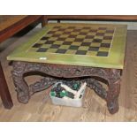 A Chinese carved hardwood coffee table with onyx chess board top and resin pieces.