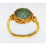 An ancient ring, probably Western Asiatic, set with a green cabochon measuring approx. 11mm in
