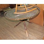 A large Benares type brass top table with folding wooden base, diameter 116cm.