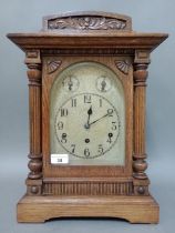 An oak cased mantle clock with arched brass dial, German three spring movement, striking on five