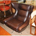A vintage brown leather wingback swivel lounge chair.