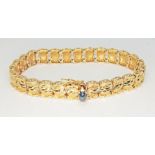 A modern bracelet set with a sapphire cabochon, the flat bottom oval stone displaying slight