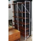 A Ladderax shelving system, comprising three white ladders and fourteen teak shelves.
